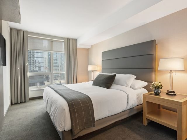 Wooden bedside table with lamp beside a bed